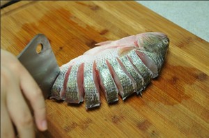 將鱸魚清洗干凈，從脊椎處切斷至腹部，腹部保留1cm左右不要切斷。