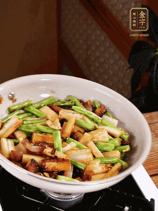 油熱下蒜末、干辣椒、醬肉煸炒出香味，依次下藕條、豆角翻炒均勻
